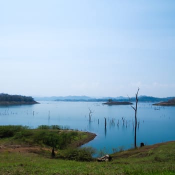 image of blue lake , mountains and dead trees of the dam