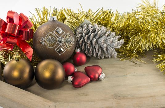 christmas balls red bow and golden decoration on wooden plate