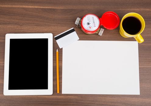 Blank paper with tablet and blank card on wooden table