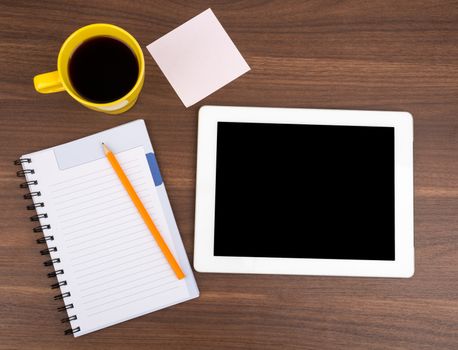 Blank copybook with tablet and sticker on wooden table