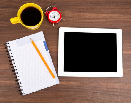 Blank copybook with tablet and alarm clock on wooden table