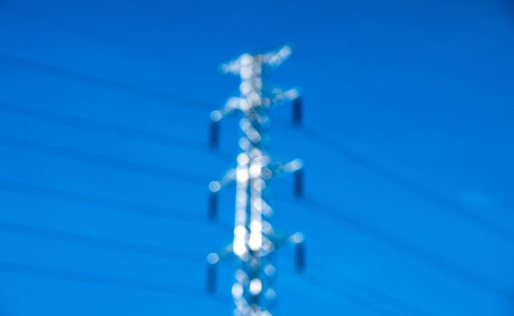 Blurry high voltage post or power transmission line tower and blue sky