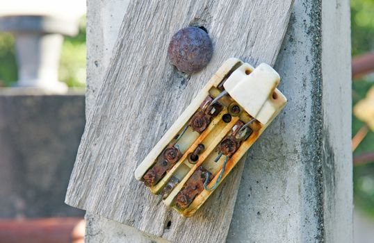 Old retro and broken dirty rust electric circuit breaker mounting on wooden outdoor panel