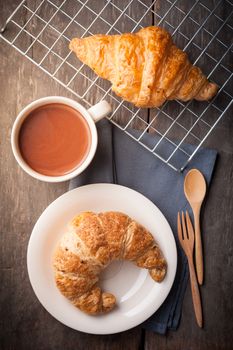 Butter croissant and whole wheat croissant with a cup of hot chocolate on wood table with morning scene