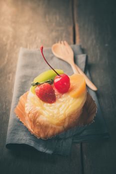 Fruit danish pastry on wood table in morning time with film filter effect