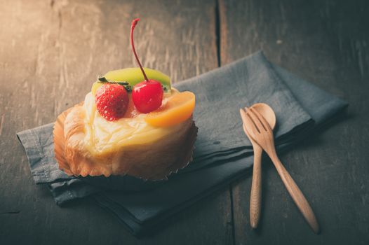 Fruit danish pastry on wood table in morning time with film filter effect