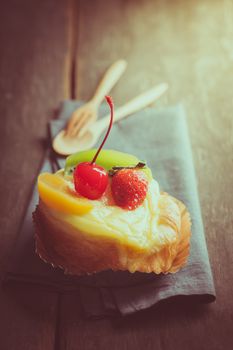 Fruit danish pastry on wood table in morning time with film filter effect