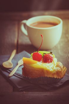 Fruit danish pastry with hot chocolate on wood table in morning time with film filter effect