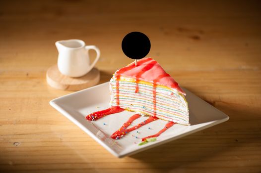 Rainbow crepe cake with black label on top in afternoon low key scene