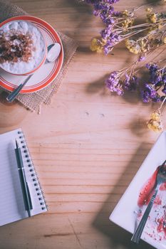 Wood table background with blank area for text or message, opened notebook, pen and a cup of hot coffee as frame in afternoon time with film filter effect