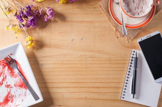 Wood table background with blank area for text or message, opened notebook, pen and a cup of hot coffee as frame in afternoon time