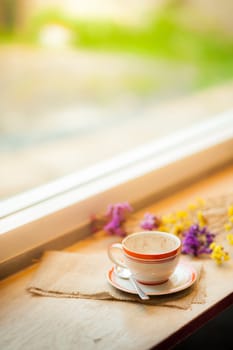 Coffee cup on wood bar beside window at coffee shop in afternoon time