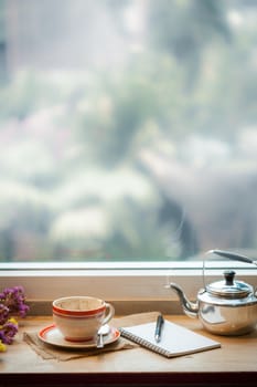 Coffee cup and opened notebook on wood bar at coffee shop in morning time of winter season