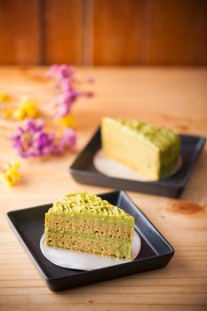 Green tea cake in black ceramic dish on wood table in afternoon time
