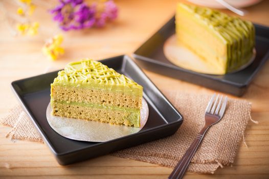 Green tea cake in black ceramic dish on wood table in afternoon time