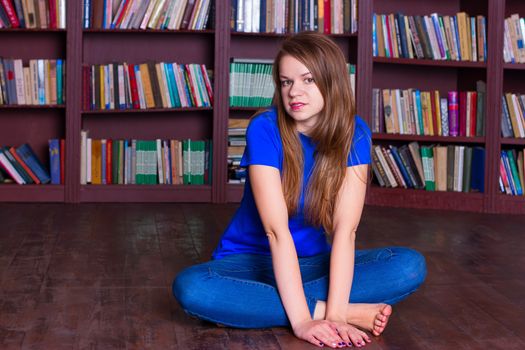 A girl sits on the floor in the library