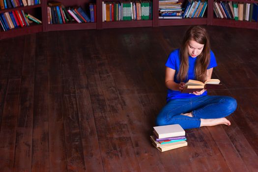 A girl sits on the floor in the library