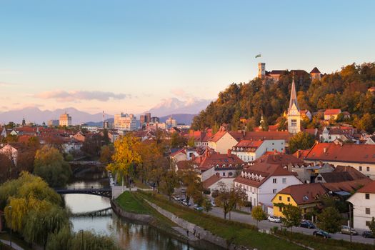Cityscape of the Slovenian capital Ljubljana at sunset. Ljubljana castle on hill above town. River Ljubljanica running trough city center. Karavanke mountains in background.