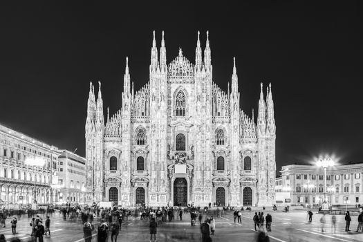 Milan Cathedral, Duomo di Milano. Famous gothic cathedral church of Milan, Italy, Europe. Black and white image shot at dusk from square full of people.
