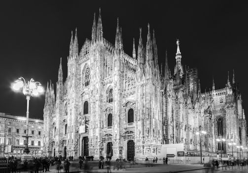 Milan Cathedral, Duomo di Milano. Famous gothic cathedral church of Milan, Italy, Europe. Black and white image shot at dusk from square full of people.