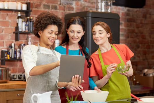 cooking class, friendship, food, technology and people concept - happy women with tablet pc computer in kitchen