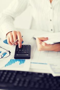 business, office, school and education concept - woman hand with calculator and papers