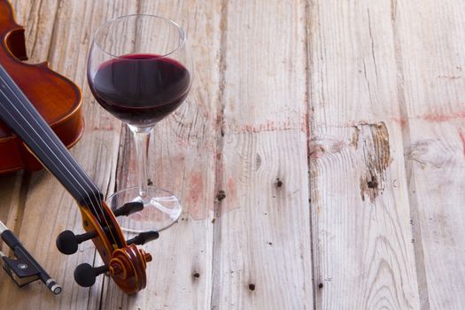 Pair of Violin Instrument and Glass of Wine Wine on a Wooden Floor with Copy Space on the Right.