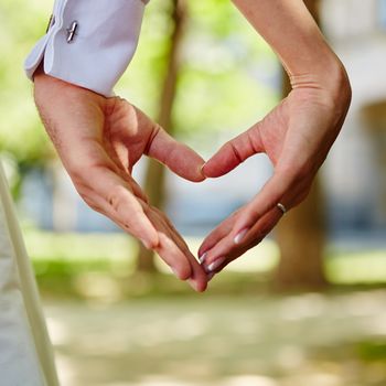 hands of bride and groom in a shape of heart