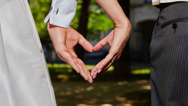 hands of bride and groom in a shape of heart