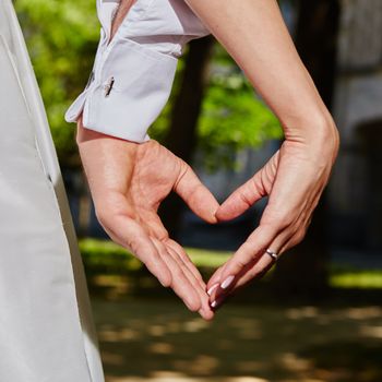 hands of bride and groom in a shape of heart