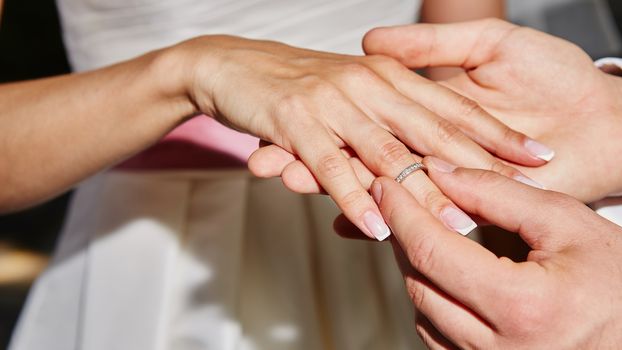 groom puts on the ring on the finger of the bride