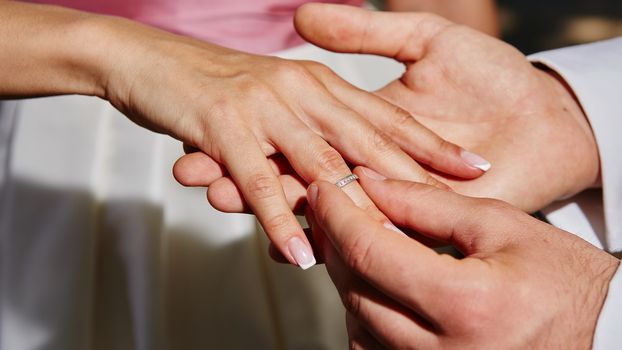 groom puts on the ring on the finger of the bride