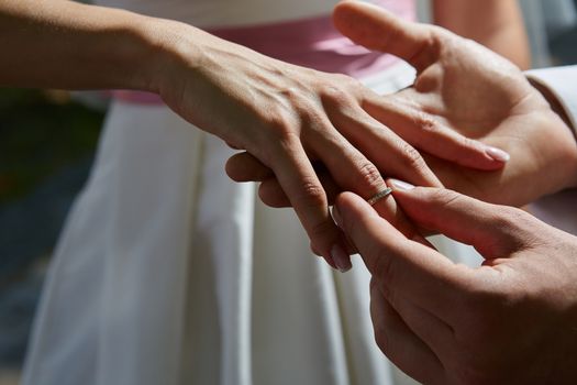 groom puts on the ring on the finger of the bride