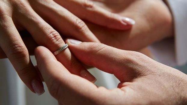 groom puts on the ring on the finger of the bride