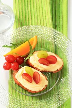 Slices of bread roll with cheese spread and grapes