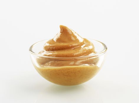 Swirl of spicy mustard in a small glass bowl