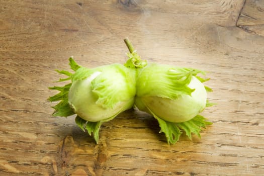 Pair of unripe hazelnuts on wooden background
