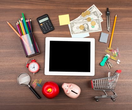 Shopping cart with money and piggy bank on wooden table