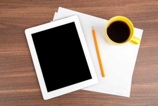 Tablet with blank paper and coffee on wooden table