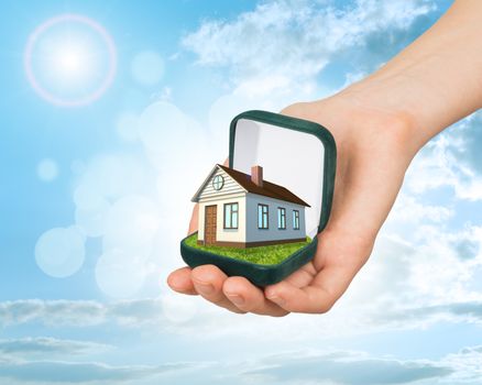 Empty ring box house in humans hand on blue sky background