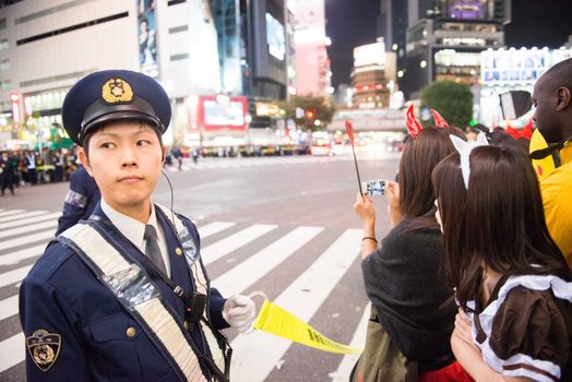 JAPAN, Tokyo : A policeman deals with the crowd as people take part in a Halloween parade in Tokyo on October 31, 2015. Tens of thousands of people gathered at Tokyo's Shibuya fashion district to celebrate Halloween.