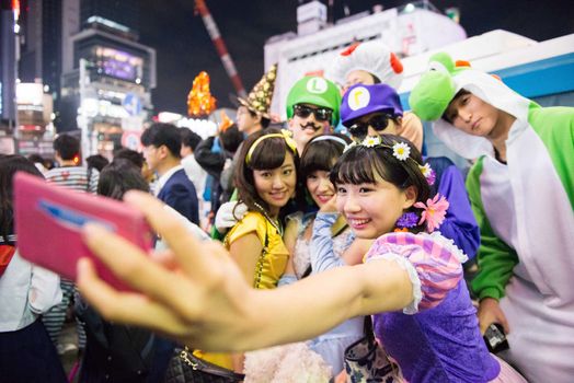 JAPAN, Tokyo : People wear costumes as they pose for a selfie while taking part in a Halloween parade in Tokyo on October 31, 2015. Tens of thousands of people gathered at Tokyo's Shibuya fashion district to celebrate Halloween.