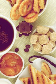 Breakfast Concept with Coffee Cup, Chocolate, Sugar Cubes, Toasts, Apricot Jam, Milk and Puff Pastry on Checkered background. Retro Styled