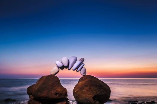 Arch of pebbles between of stones on the seashore