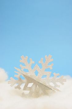 A closeup view of a decorative winter snowflake over a blue background.