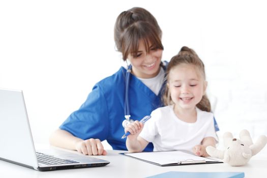 Child patient and young female doctor writing diagnosis