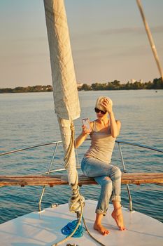 Pretty young female tourist makes selfie on yacht at sunset