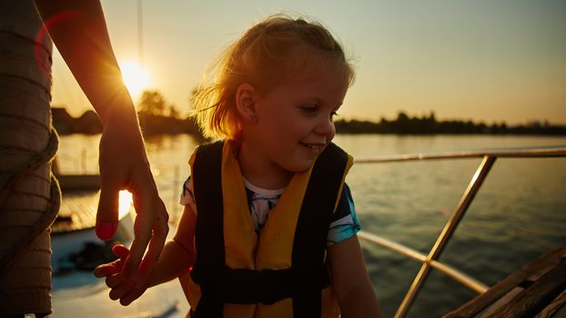 Little girl enjoying ride on yacht at sunset