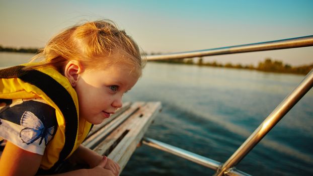 Little girl enjoying ride on yacht at sunset