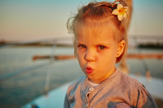 Little girl enjoying ride on yacht at sunset